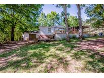 Inviting home featuring a charming covered porch and detached garage, nestled among mature trees on a spacious lot at 7733 Skyline Dr, Sherrills Ford, NC 28673