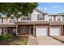 Charming two-story townhome with brick and white siding, featuring a one-car garage and inviting front entrance at 104 Clydesdale Ct, Matthews, NC 28104