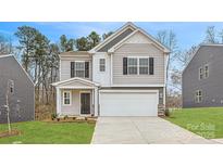 Charming two-story home featuring a two-car garage and inviting front porch, set in a landscaped yard at 118 Dorian Pl, Troutman, NC 28166