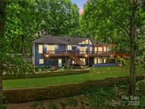 Beautiful blue home featuring a large deck, lush landscaping, and mature trees offering a serene and private setting at 146 Paradise Peninsula Rd, Mooresville, NC 28117