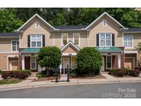 Inviting townhome exterior featuring a manicured lawn, mature trees, and a welcoming entrance at 15318 Coventry Court Ln, Charlotte, NC 28277