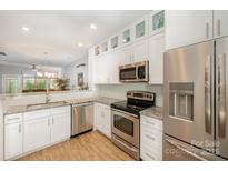 Bright kitchen features stainless steel appliances, granite counters, white cabinetry, and wood floor at 15318 Coventry Court Ln, Charlotte, NC 28277