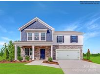 Two-story home featuring a stone and siding facade, covered front porch and two car garage at 1623 Spring Lot Dr, Edgemoor, SC 29712