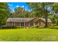 Traditional brick home featuring a well-manicured lawn and a patriotic flagpole at 1760 Jacobs Way, Sherrills Ford, NC 28673