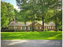 Charming single-story brick home with a lush green lawn, mature trees, and a flag pole at 1760 Jacobs Way, Sherrills Ford, NC 28673