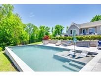 Backyard featuring a modern pool with in-water loungers, lush landscaping and outdoor seating on a patio at 1780 Sierra Rd, York, SC 29745