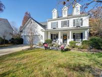 Charming two-story home with a well-manicured lawn, seating, and a welcoming front porch at 5076 Timber Falls Dr, Indian Land, SC 29707