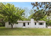 Charming white brick home featuring a well-manicured lawn and mature trees in a serene setting at 528 W Park Dr, Monroe, NC 28112