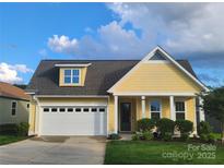Charming yellow house featuring a well-manicured lawn, inviting front porch, and a convenient attached garage at 6220 Raven Rock Dr, Denver, NC 28037