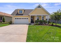 Charming yellow home featuring a two-car garage and professionally landscaped front yard at 6220 Raven Rock Dr, Denver, NC 28037
