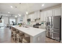 A modern kitchen is shown with stainless steel appliances, white cabinets and a large island with seating for four at 6242 Ashton Park Dr, Denver, NC 28037