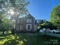 Beautiful two-story brick home featuring a landscaped front yard and lovely architectural details under a bright blue sky at 944 Evian Ln, Matthews, NC 28015