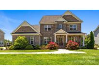 Charming two-story brick home with beautiful landscaping and a welcoming front porch at 10517 Sable Cap Rd, Mint Hill, NC 28227