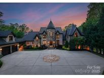 Majestic castle-like home with stone facade, turret, circular drive, and beautifully landscaped grounds at 172 Tennessee Cir, Mooresville, NC 28117