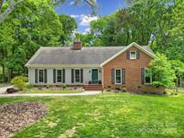 Charming home with a lush green lawn, mature trees, and a mix of brick and siding exterior at 2626 Lilly Mill Rd, Charlotte, NC 28210