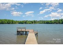 Lake view featuring a wooden dock extending into the water with a bench, against a backdrop of a clear blue sky at 4960 Longfield St, Claremont, NC 28610