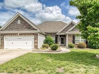 Charming single-story home featuring a brick and stone facade, attached garage, and well-manicured lawn at 5355 Hackberry Sw Ln, Concord, NC 28027