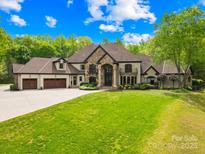 Stunning stone and stucco home featuring a three-car garage and well-manicured lawn at 8451 Ridgewood Rd, Sherrills Ford, NC 28673
