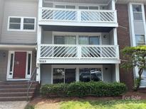 Three-story condo featuring two balconies with white cross-beamed railings, complemented by red brick and gray siding at 9325 Old Concord Rd # D, Charlotte, NC 28213