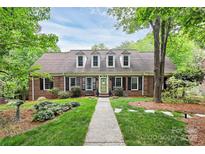 Charming brick home featuring dormer windows, a well-manicured lawn, and a welcoming walkway at 10209 Thomas Payne Cir, Charlotte, NC 28277