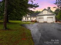 Charming home with an attached two-car garage and spacious front yard at dusk at 140 Ribbon Cir, Lincolnton, NC 28092