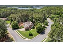 Stunning aerial view of a brick home on a large lot with mature trees and lake views at 221 Silvercliff Dr, Mount Holly, NC 28120
