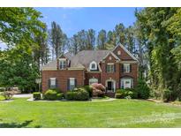 Charming two-story brick home featuring a well-manicured lawn, mature trees, and classic architectural details at 221 Silvercliff Dr, Mount Holly, NC 28120