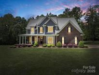 Charming two-story home with a brick and gray siding, a welcoming front porch, and landscaped yard at dusk at 270 Conifer Way, Shelby, NC 28150
