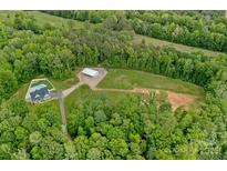 Stunning aerial view of property featuring pool, home, metal building, and wooded acreage at 270 Worthington Dr, Mt Ulla, NC 28125