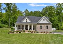 Charming brick home featuring a covered front porch and lush green lawn with mature trees at 270 Worthington Dr, Mt Ulla, NC 28125