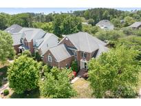 Beautiful brick home showcasing lush landscaping, mature trees, and a well-maintained lawn at 7525 Blackgum Falls Ct, Huntersville, NC 28078
