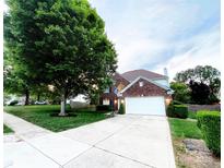 Charming two-story brick home with a well-manicured lawn, large tree, and long driveway leading to a two car garage at 8218 Lynnewood Glen Dr, Charlotte, NC 28269