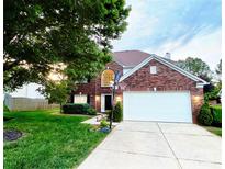 Charming two-story brick home featuring an attached two-car garage and well-manicured lawn with mature tree at 8218 Lynnewood Glen Dr, Charlotte, NC 28269