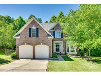 Charming brick two-story home featuring a well-manicured lawn, two-car garage, and mature trees at 9700 Stewart Spring Ln, Charlotte, NC 28216
