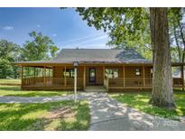 Charming log cabin with a covered porch, mature trees, and a well-manicured lawn at 993 Jackson Rd, Fort Lawn, SC 29714