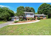 Charming two-story home with a well-manicured front yard, mature trees, and a two-car garage at 1004 Midwood Dr, Monroe, NC 28112