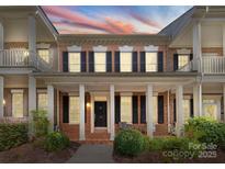 Charming two-story brick home with a welcoming front porch and beautiful landscaping at sunset at 155 Harper Lee St, Davidson, NC 28036