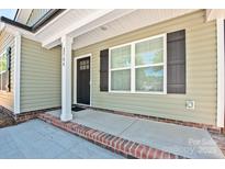 Charming front porch featuring brick detail, a black front door, and green siding at 2502-2504 Glendale Ave, Kannapolis, NC 28081