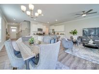 Open-concept living room showcasing modern decor, an elegant chandelier, and seamless flow to the kitchen at 574 Altamonte Dr, Clover, SC 29710