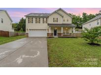 Charming two-story home featuring a spacious lawn, a two-car garage, and a welcoming front porch at 7031 Woodbridge Valley Cir, Charlotte, NC 28227