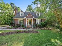 Charming two-story home featuring a well-manicured lawn, landscaped garden, and inviting front porch with decorative flower pots at 8017 Nathanael Greene Ln, Charlotte, NC 28227