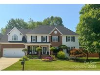Charming two-story home featuring a manicured lawn, brick accents, black shutters, and a well-maintained front garden at 8056 Stevens Mill Rd, Matthews, NC 28104