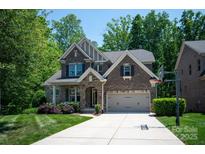 Charming two-story brick home boasts a manicured lawn, stone accents, and a basketball hoop on a paved driveway at 938 Rock Forest Way, Fort Mill, SC 29707