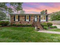 Charming brick home with mature landscaping, black shutters and inviting front porch at 1005 N Main St, Mount Holly, NC 28120