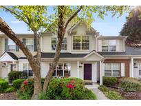 Charming townhome featuring a purple door, well-maintained landscaping, and a welcoming front porch at 12536 Hennigan Place Ln, Charlotte, NC 28214