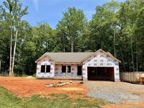 New construction home with an unfinished brick foundation and a spacious two-car garage in a wooded area at 155 Putney Ct, Salisbury, NC 28147