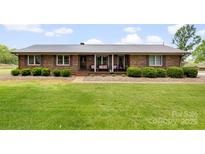 Charming brick ranch home featuring a covered front porch with updated metal roof and manicured landscaping at 1870 Sloan Rd, Mt Ulla, NC 28125