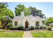 Charming white Tudor-style home with a beautiful wooden door and manicured landscaping at 2033 Charlotte Dr, Charlotte, NC 28203