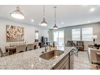 Modern kitchen featuring granite counters, stainless steel sink, and an open floor plan to the dining and living areas at 2460 Hedgecliff Rd, Kannapolis, NC 28025