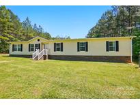 Single level home with yellow siding and black shutters in a green lawn setting at 2784 Leadoff Rd, Lancaster, SC 29720